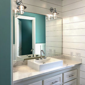 A bathroom vanity with two lighting fixtures and a large mirror